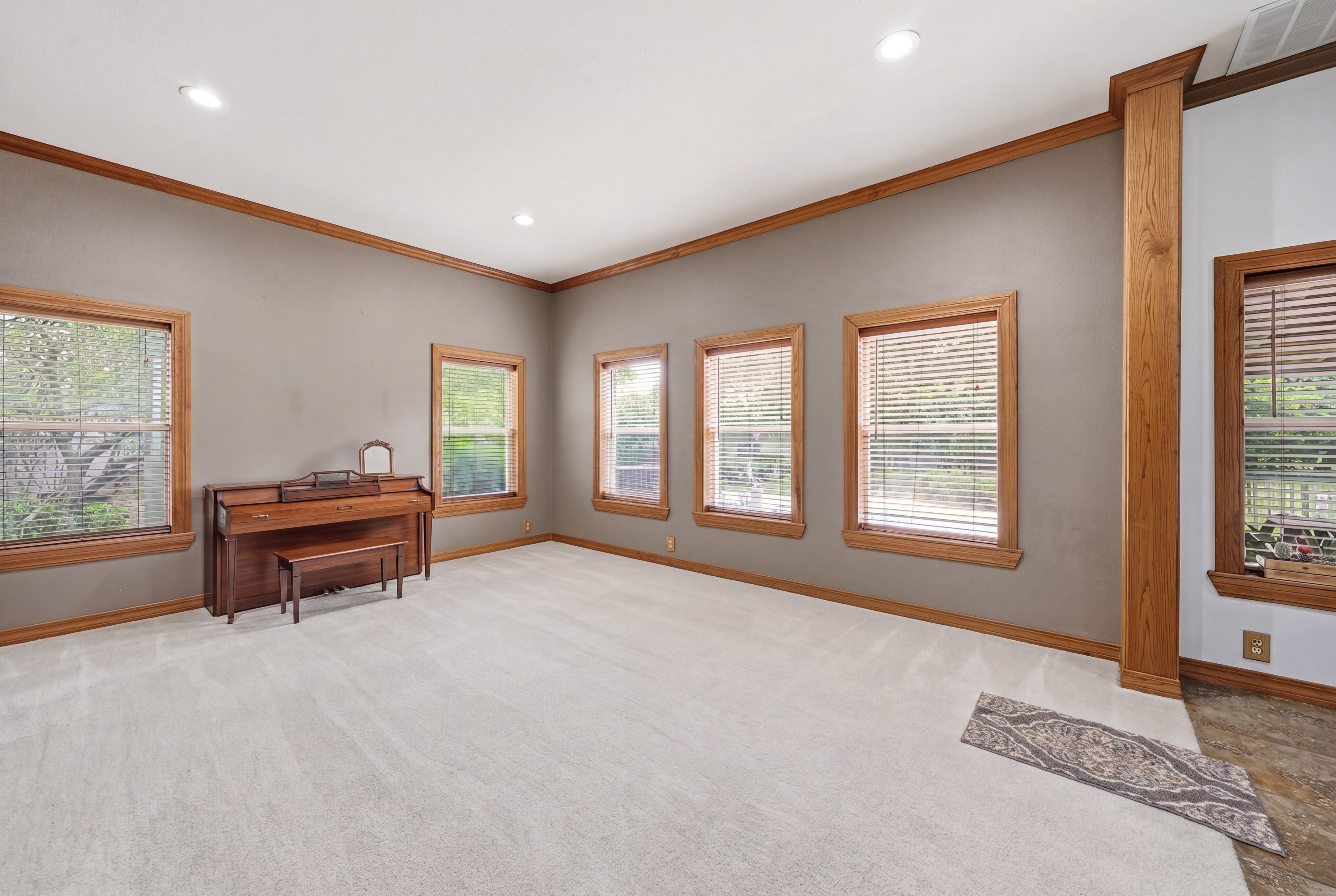 Formal dining area with multiple windows trimmed in stained wood, capable of hosting large gatherings.