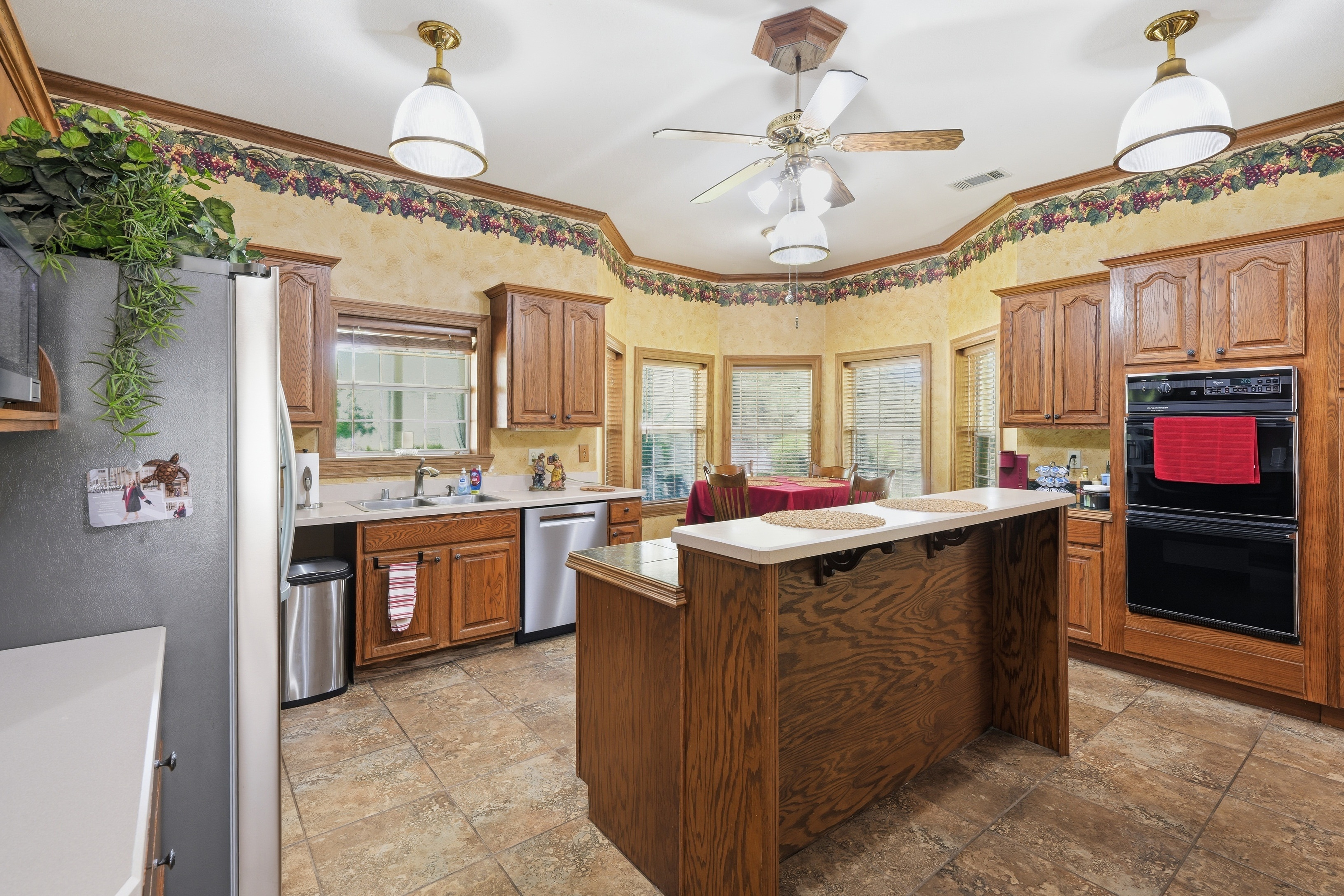 Kitchen with center island in 12-inch marble tile, inset four-burner electric cooktop, and raised breakfast bar for four.