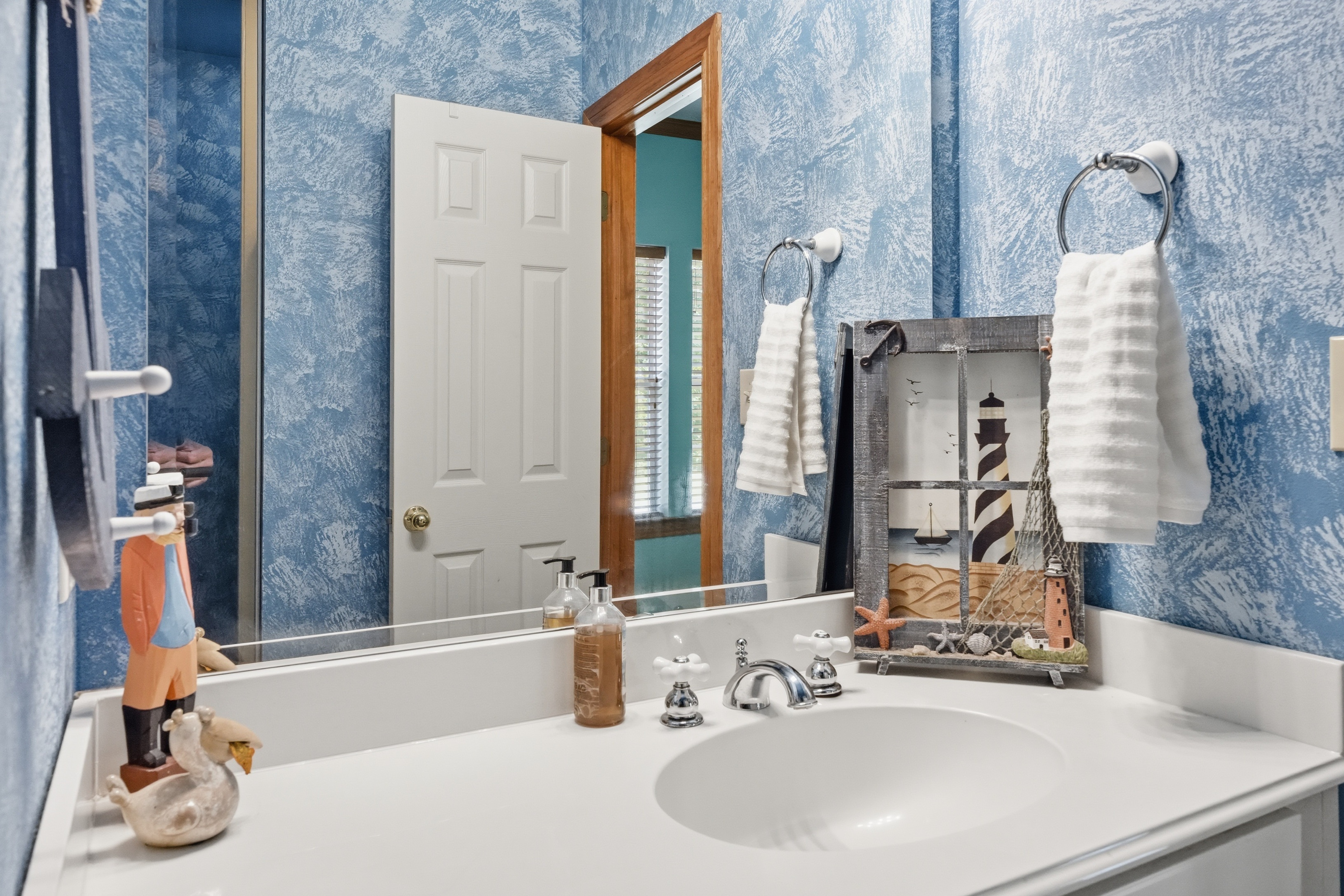 Secondary bathroom with cultured marble vanity, four-light wall sconce, and tile-surround tub-shower.