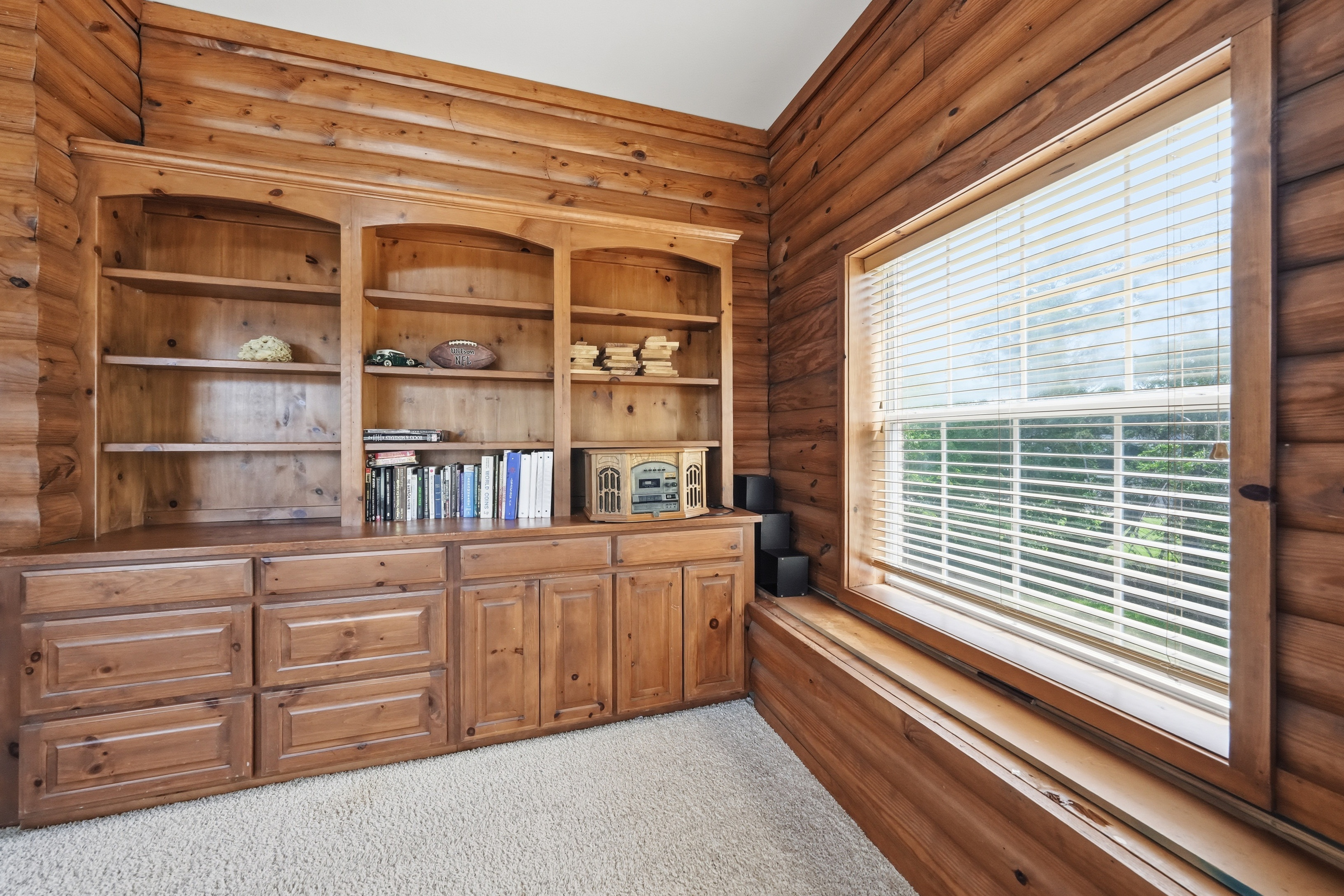 Built-in window seat with bookshelf and cabinetry, overlooking the backyard from the cabin retreat.