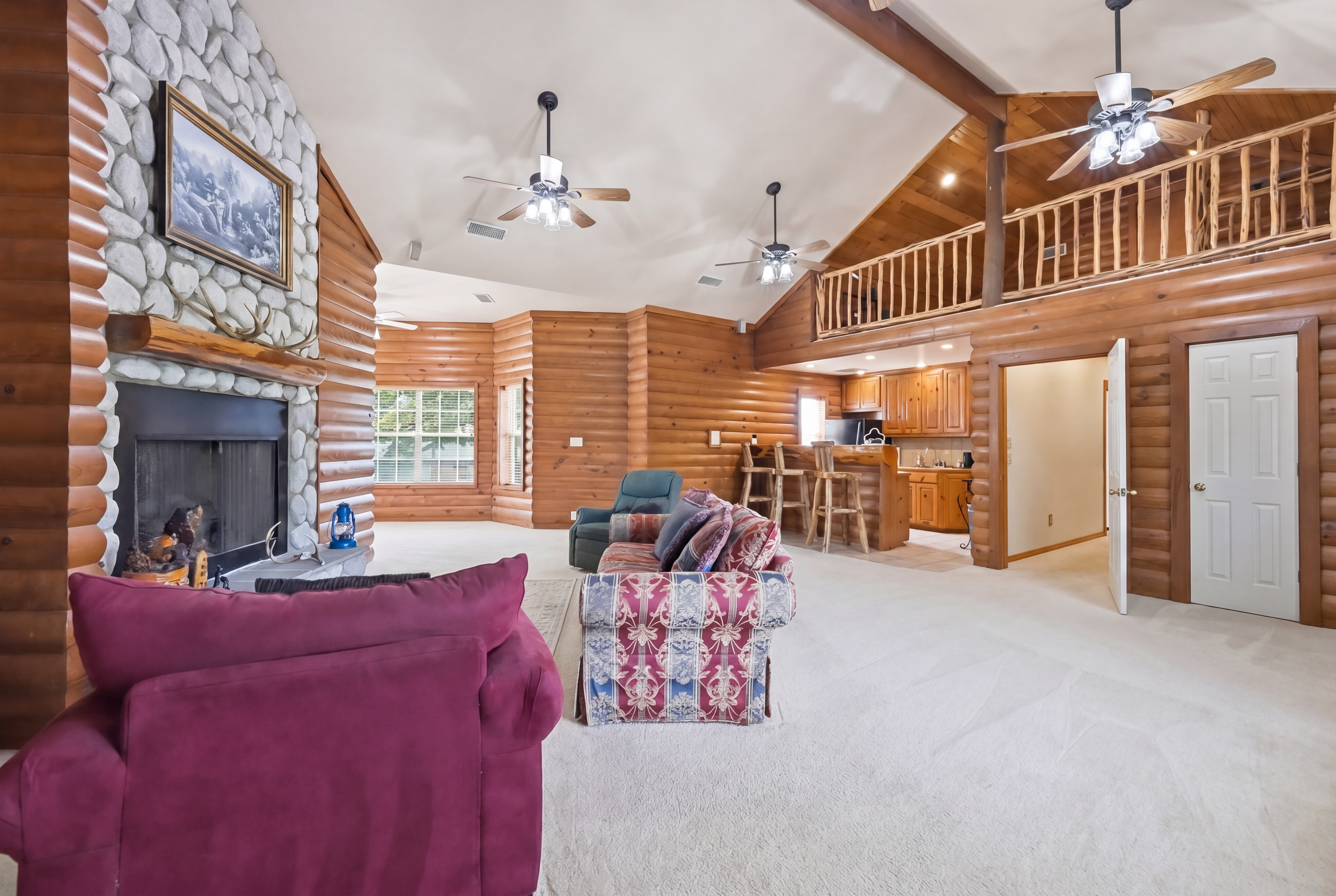 River-rock floor-to-ceiling fireplace in the great room with double mantel, natural cedar log shelf, and slate sitting hearth.