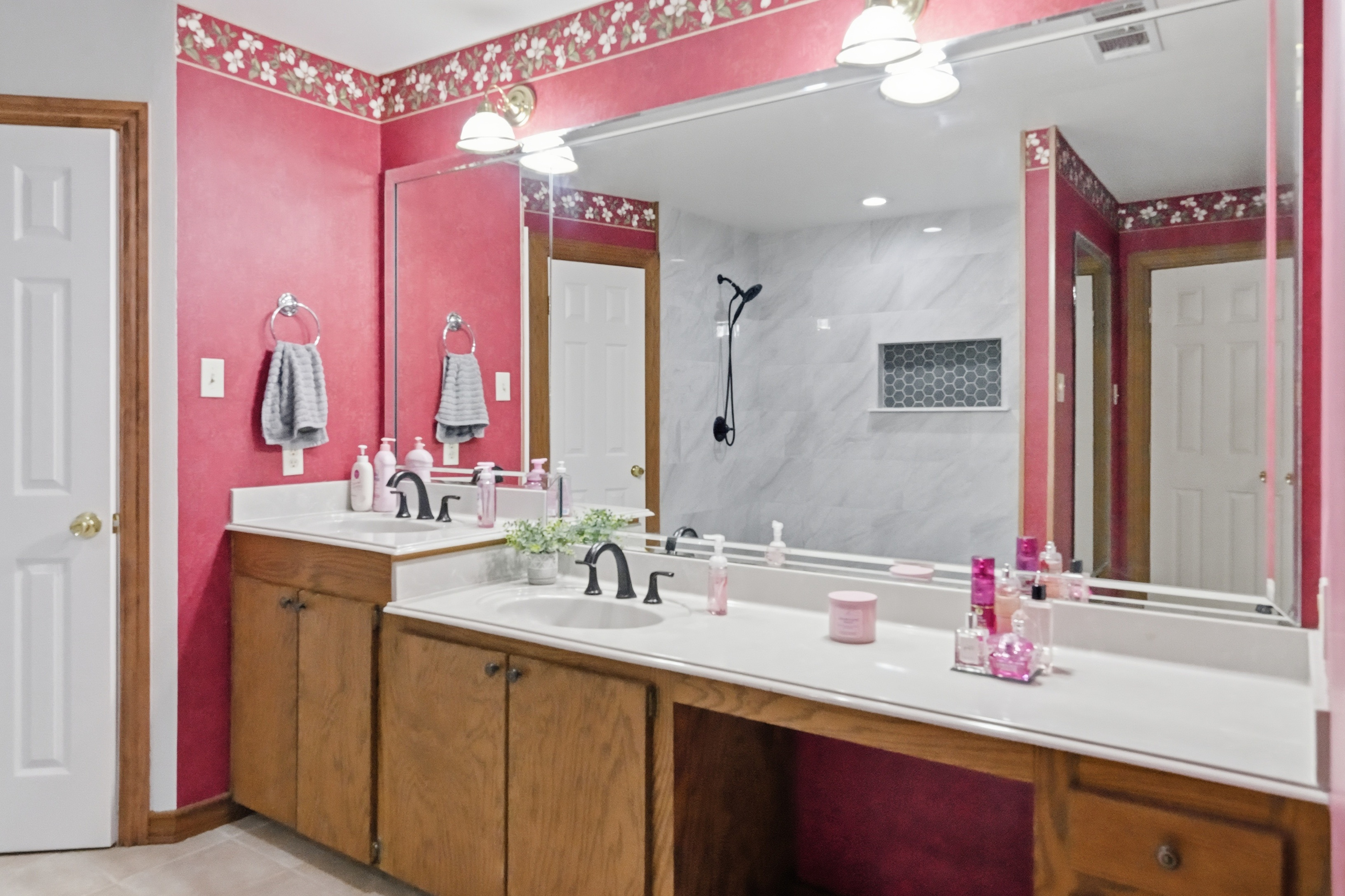 Primary bathroom with tile flooring, cultured marble double vanity, and walk-in shower.