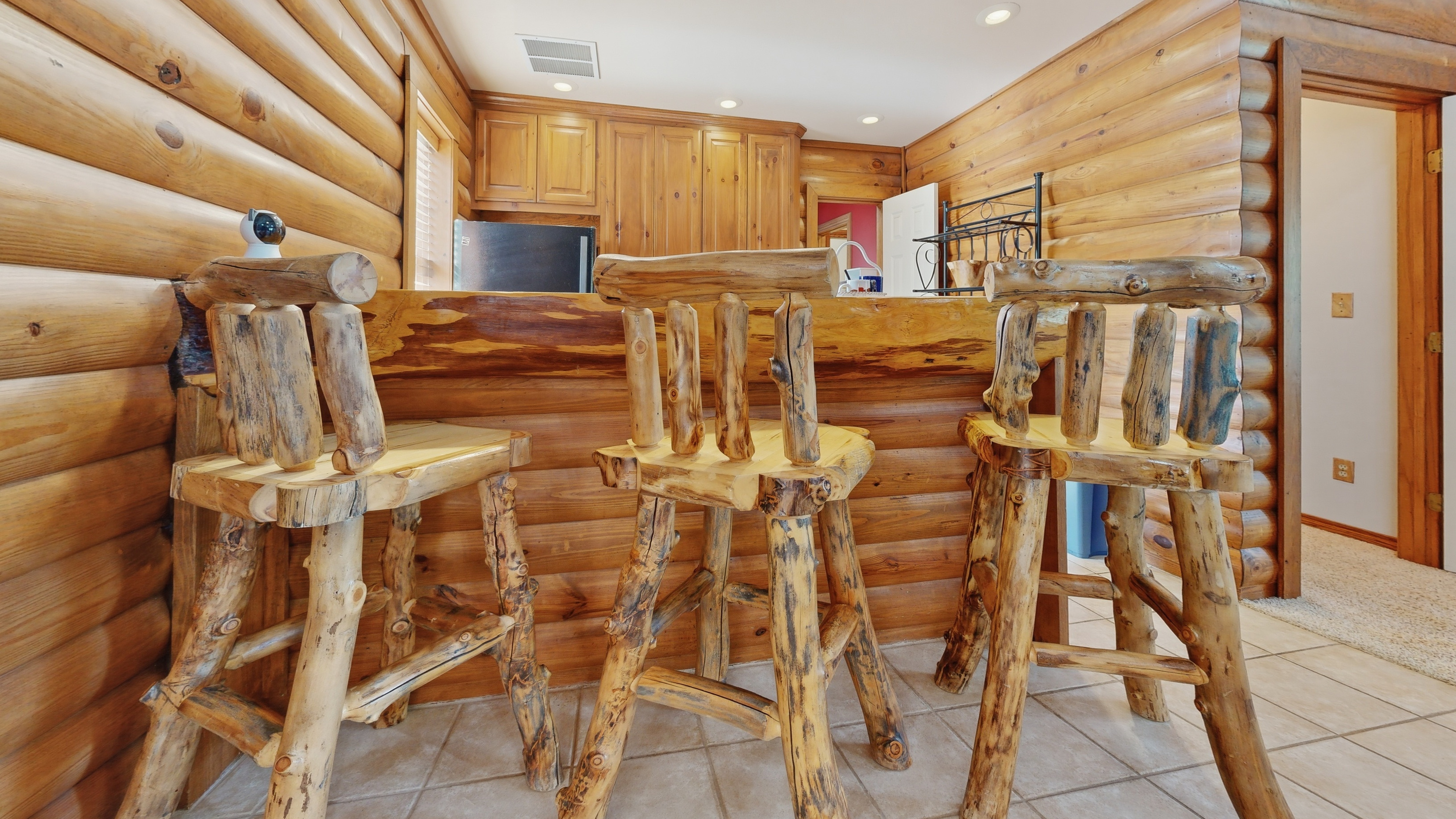 Hand-hewn cedar log barstools at the kitchenette breakfast bar in the log-cabin retreat.