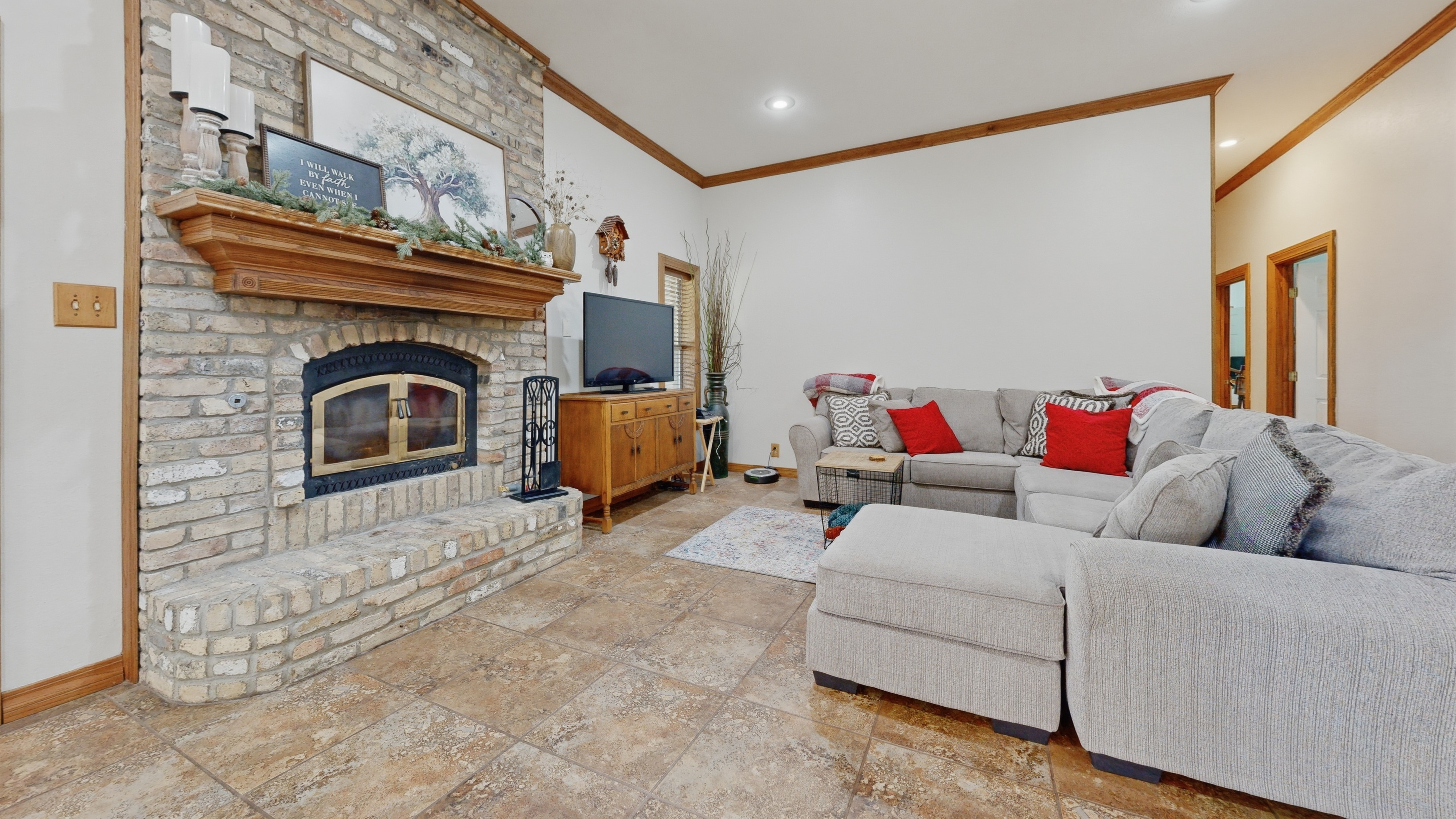 Downstairs living room with floor-to-ceiling brick fireplace, custom iron firebox with brass-and-glass doors, arched soldier surround, and Chicago brick sitting hearth.