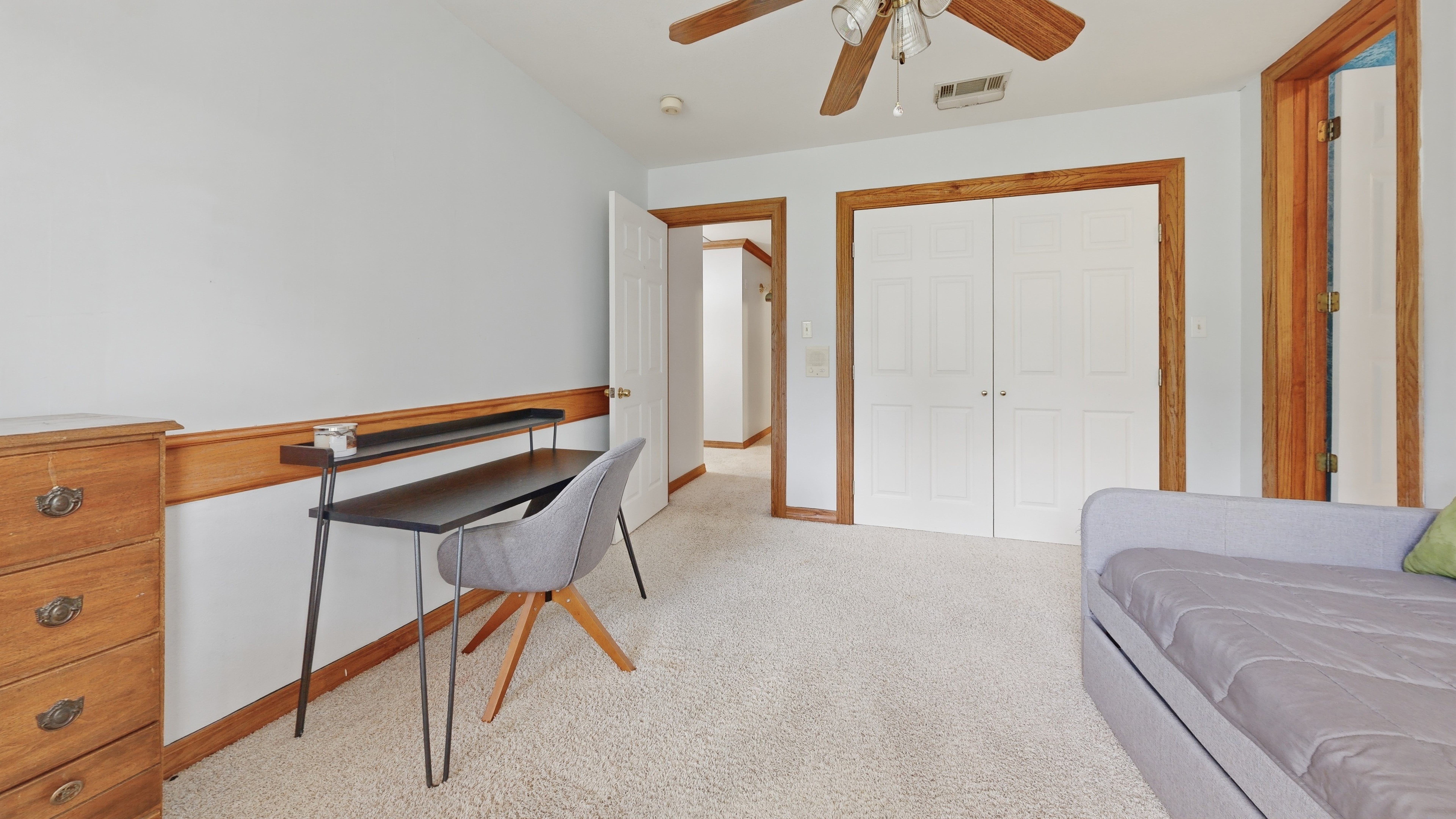 Secondary bedroom with desk, daybed, and double-door closet.