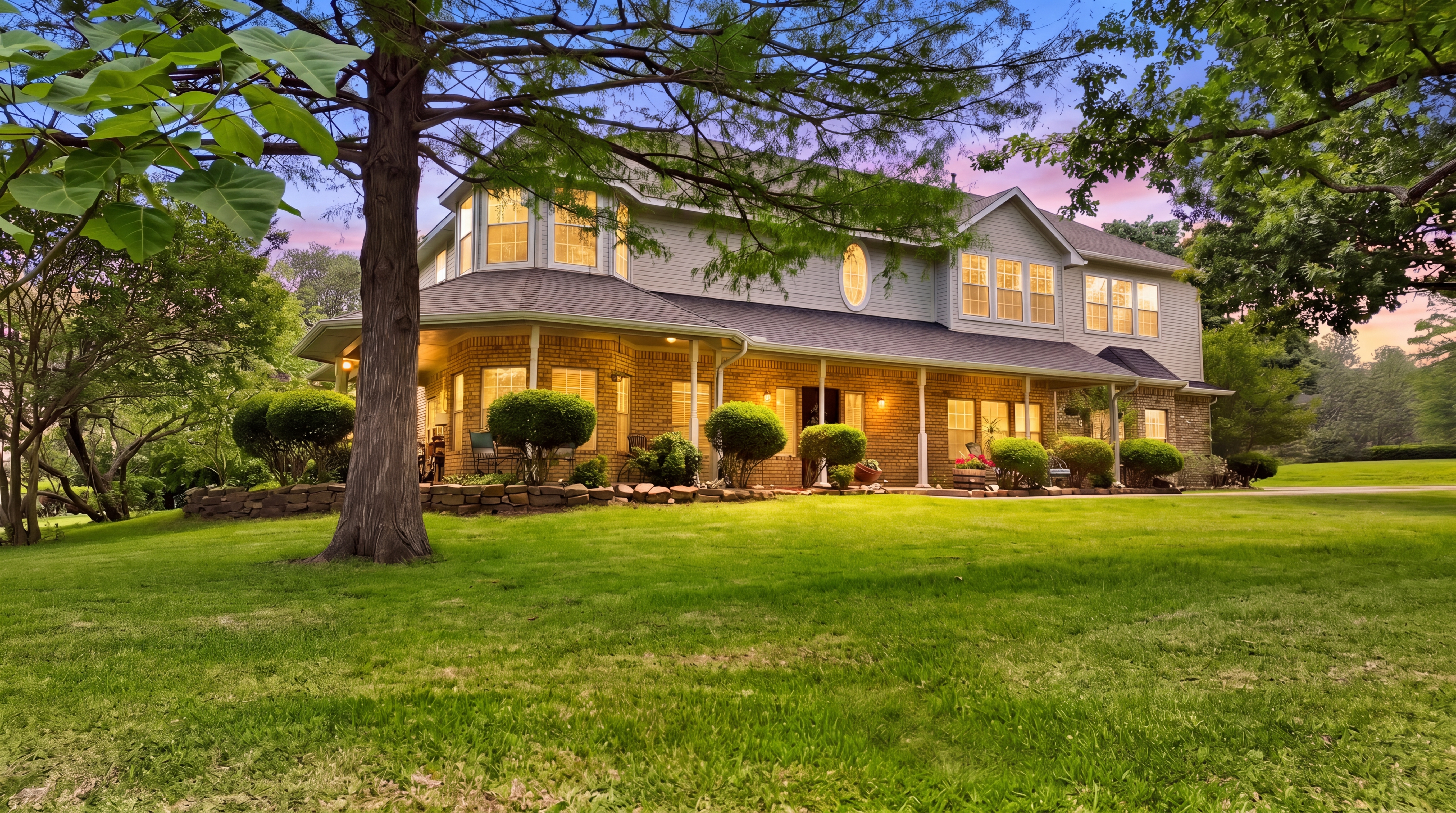 Side angle of the home at twilight, showing the bay window of the breakfast nook and old-growth tree canopy.